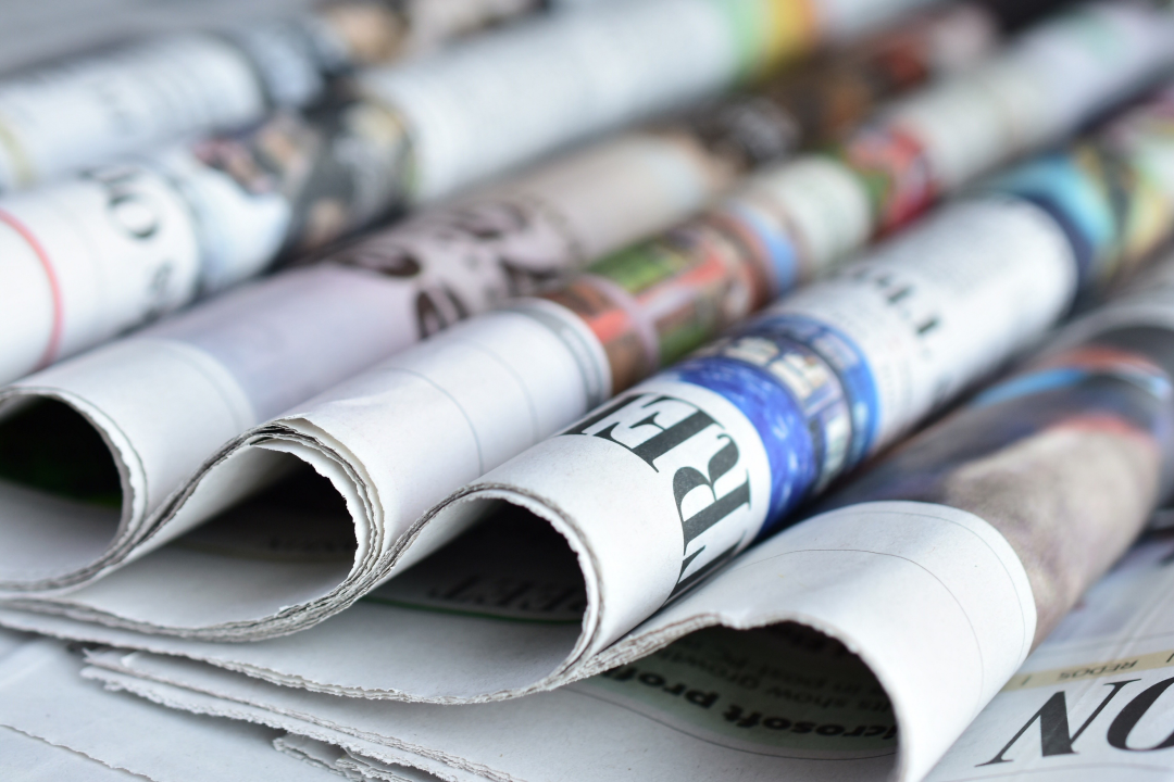 Overlapping newspapers laid on table top.