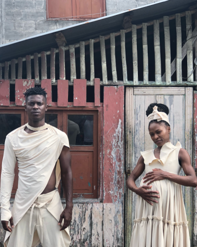 detrassura Man and woman dressed in white standing in front of wooden house