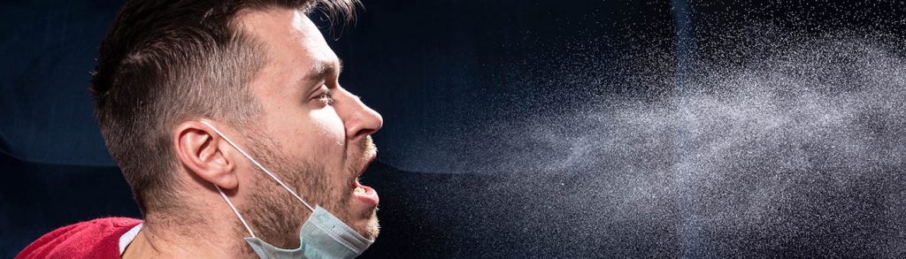 A man coughs, showing droplets dispersing.