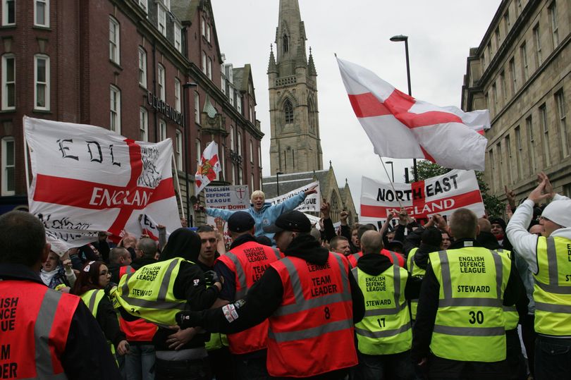 Marchers from the racist English Defence League carry flags down an English street