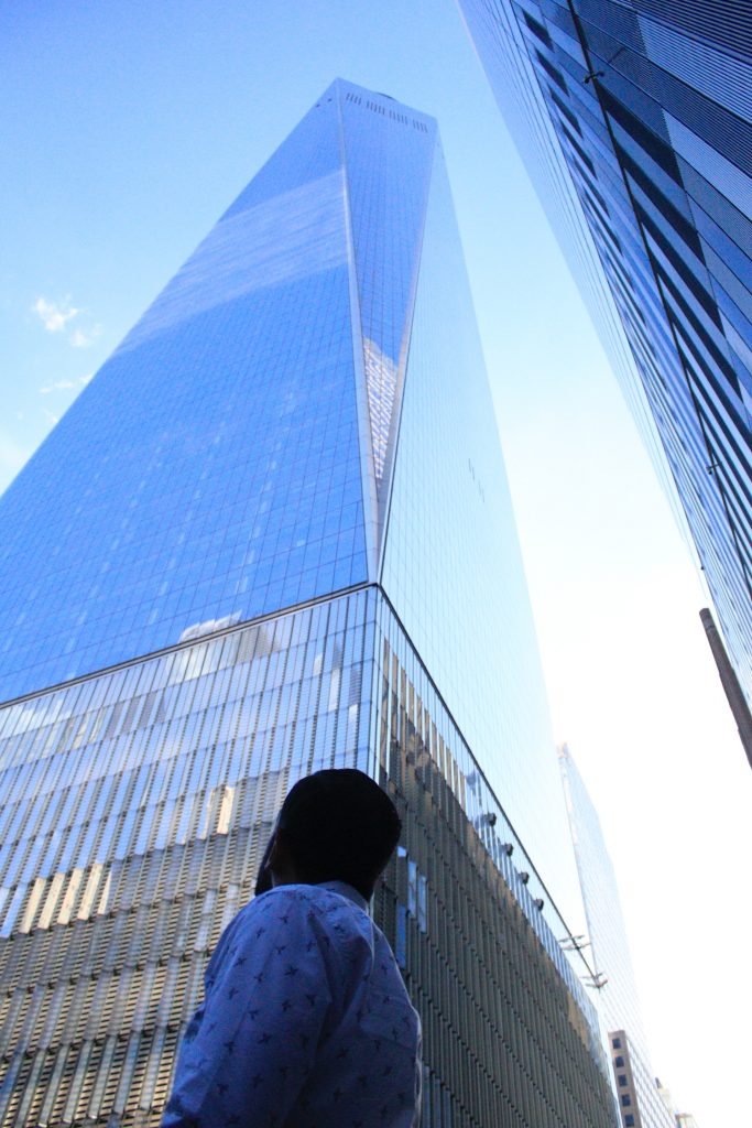 A man looks up at a huge glass skyscraper