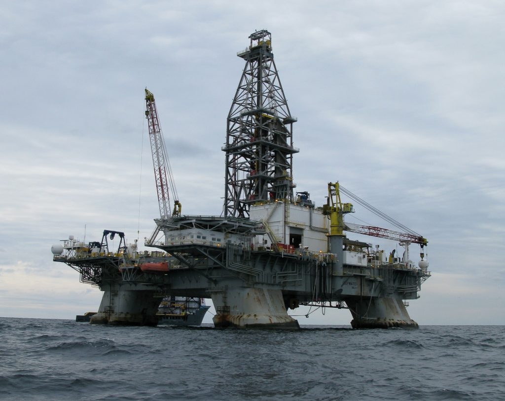 An oil rig rises out of grey seawater