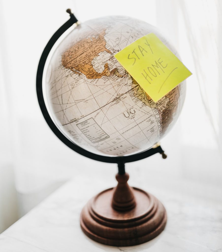 A globe with a post-it note reading 'stay home' attached to it