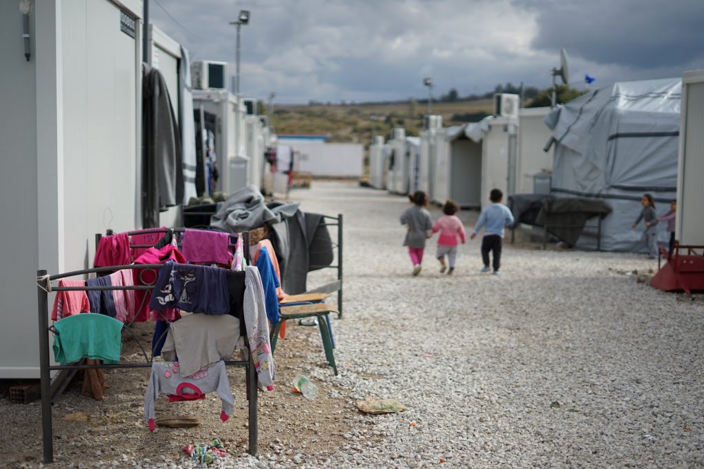 Children walk through the temporary buildings of a refugee camp