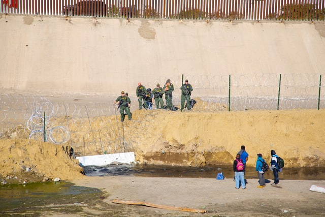 Migrants wait at a guarded border