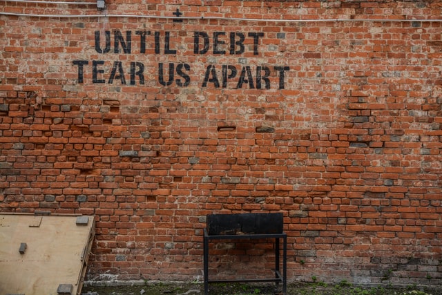 Text on a wall reading "until debt do us part."