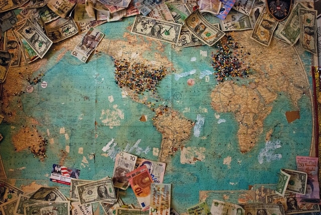 A map of the world, surrounded by scattered dollar bills