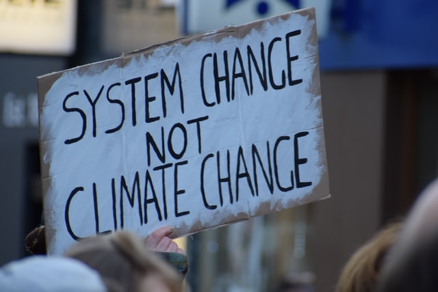 A placard reading "system change not climate change,"