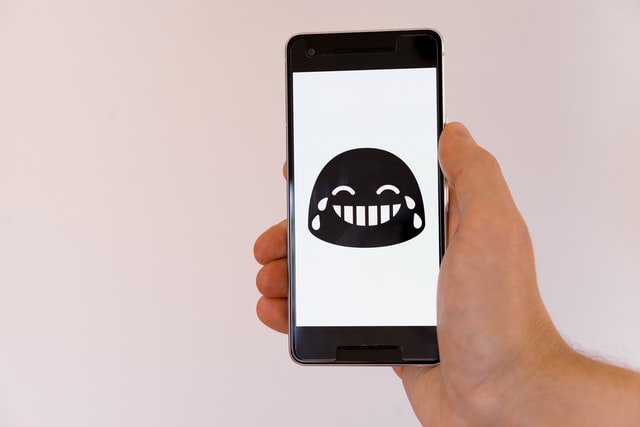 A smartphone with a laughing face on the screen