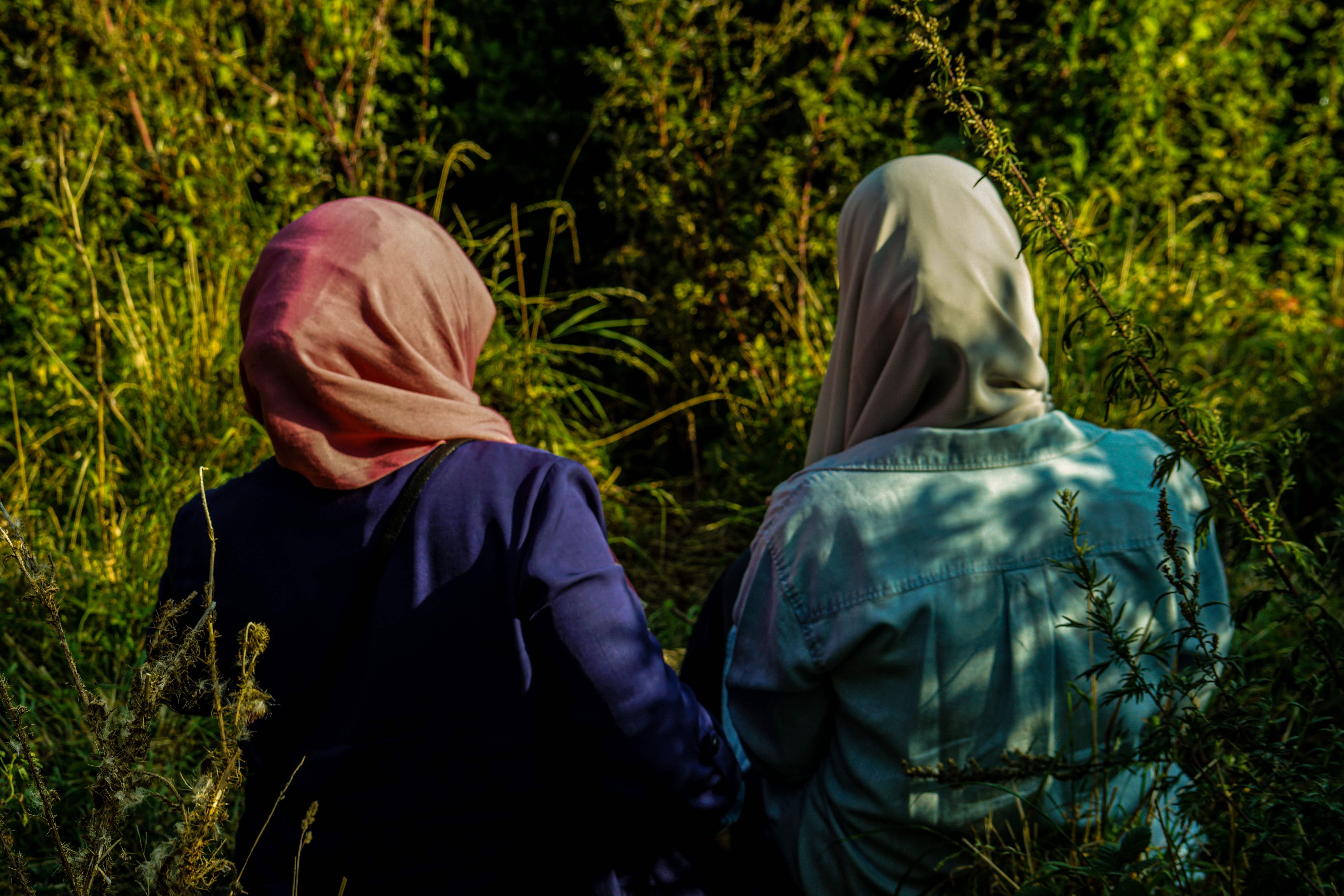 john-crozier-NJzDmlfZWz4-unsplash Two women wearing hijabs sit by a river