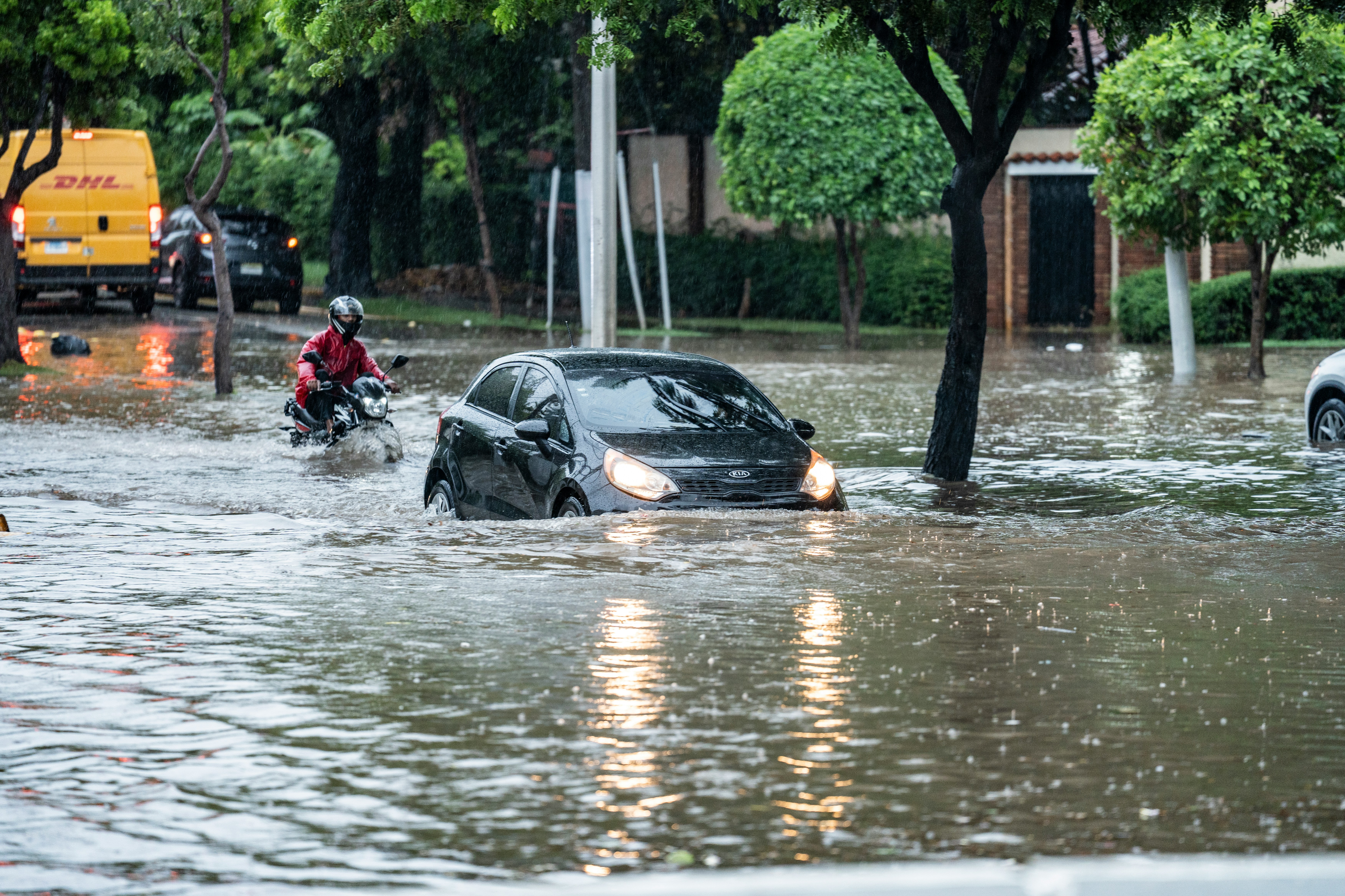 Frankie aldward-castillo-Tf7ysdubEHE-unsplash A car and a motorbike try and move through a heavy flood