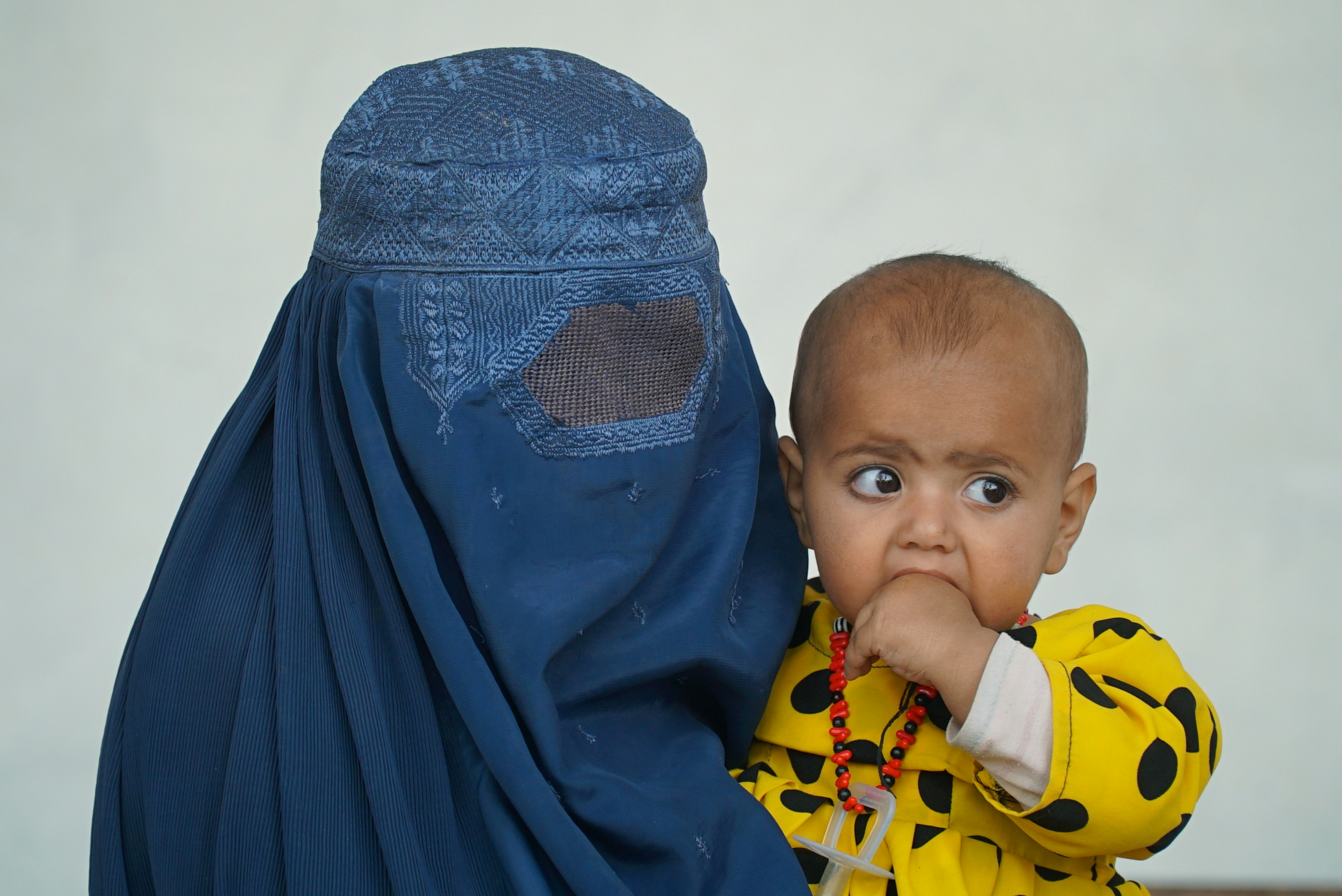 A woman in Afghanistan with a full face covering holding her baby