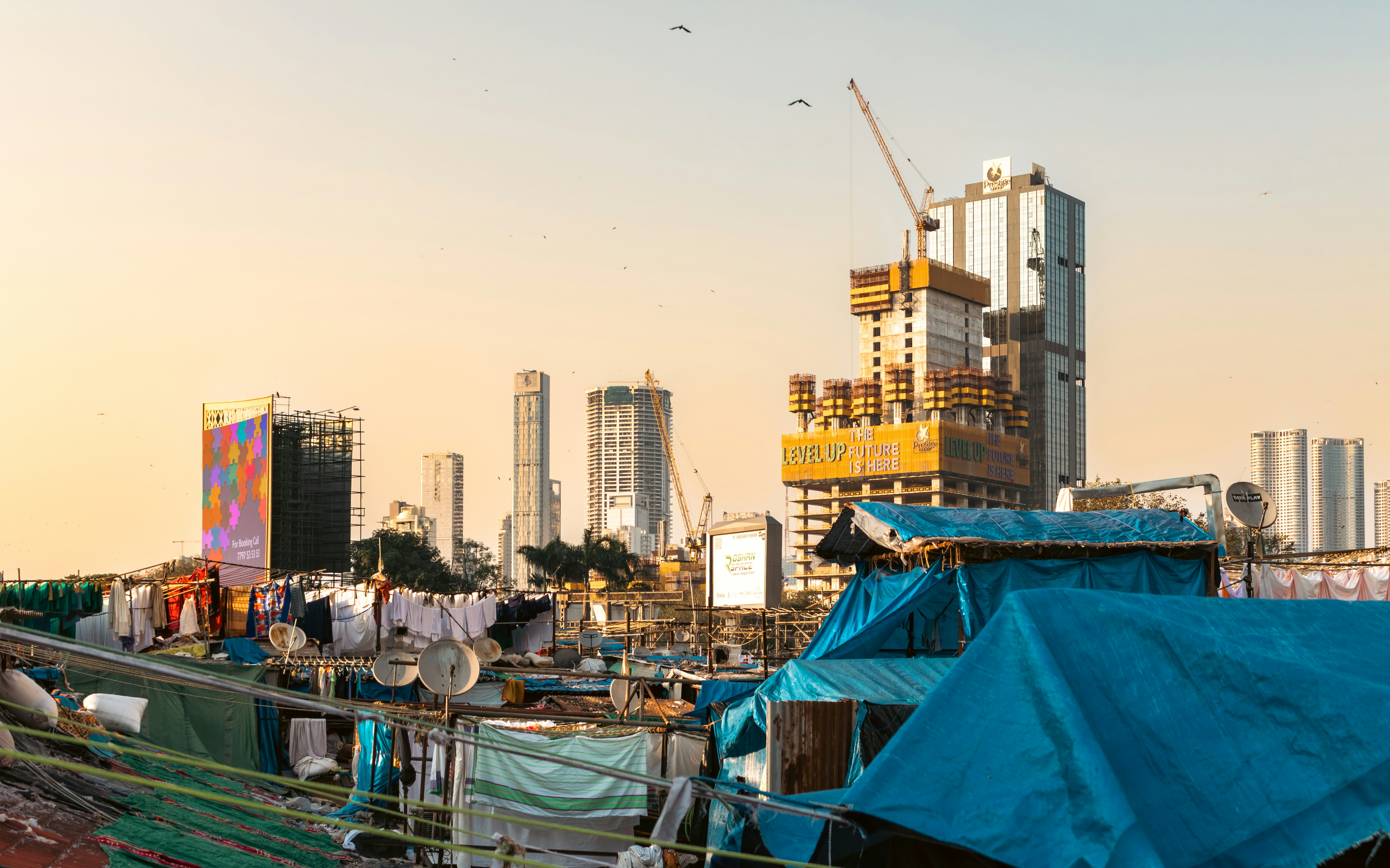 A shanty town with a blue tarpaulin next to a skyscraper