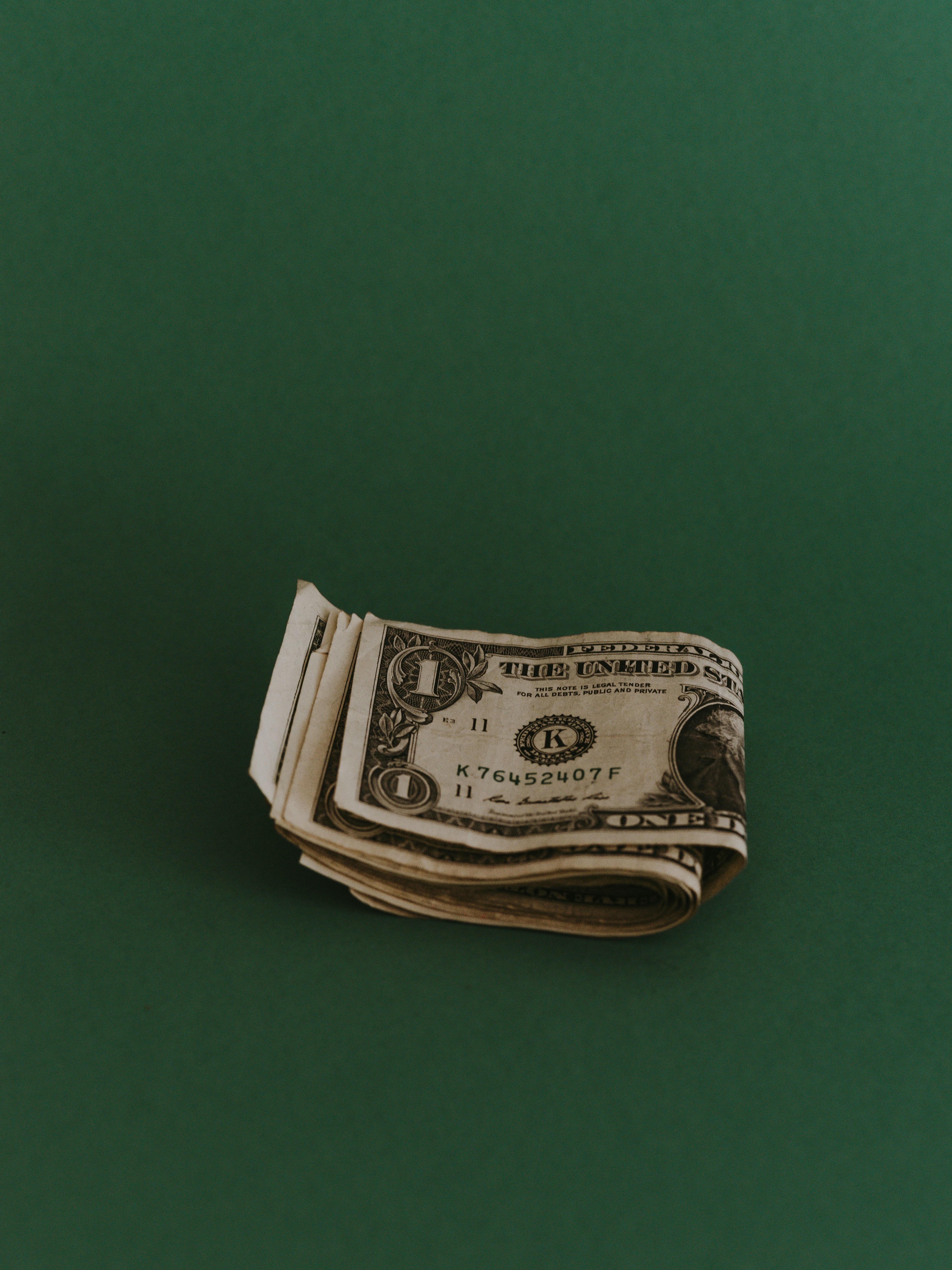 A folded set of one dollar bills on a green table