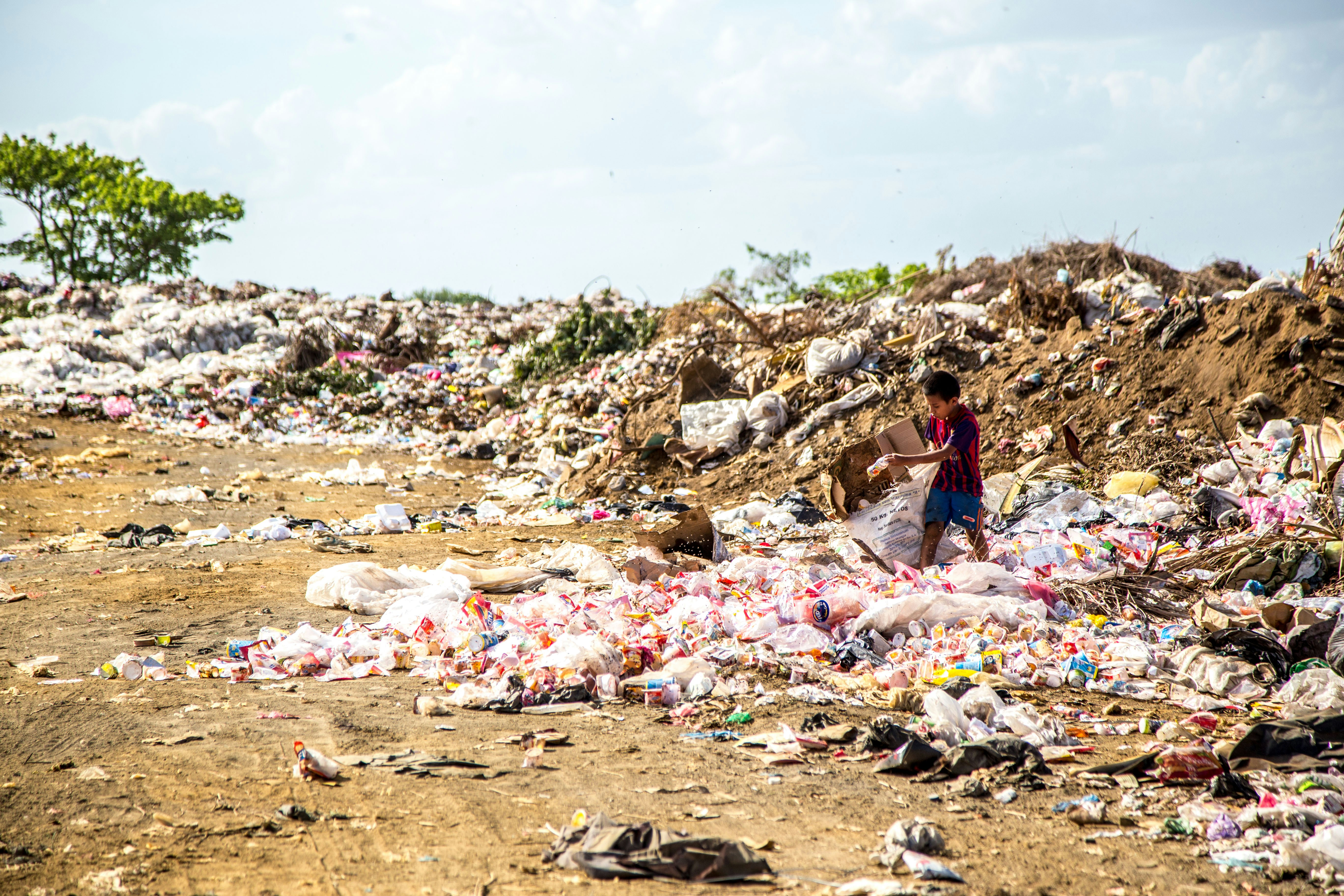 A boy tipping more waste onto a landfill site
