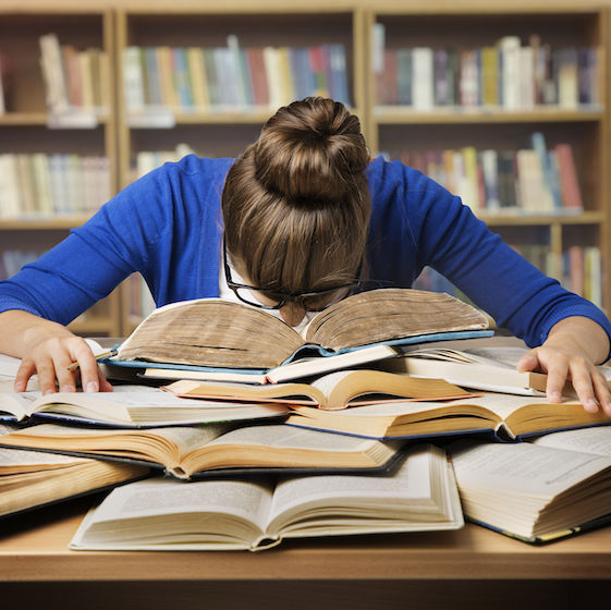 Image showing a woman with her head down in a pile of books