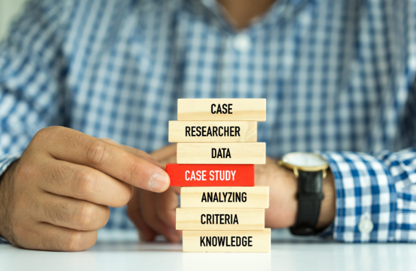 Image of a man stacking Jenga blocks with various research related issues written on them