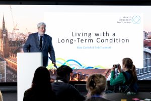 A speaker onstage with a presentation about living with a long-term condition.