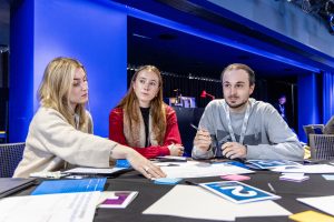 Three people at a table looking at printed materials.