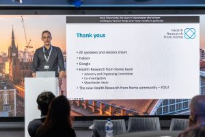 A speaker on stage presenting from a slideshow.