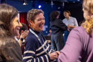 A woman laughing while talking to someone else.
