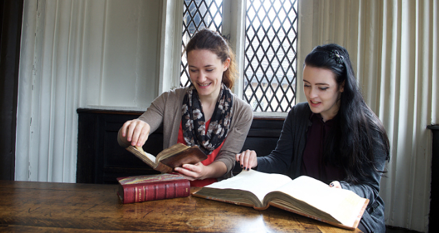 Student and academic supervisor looking at old books