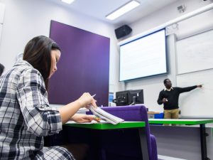 Female student watching a lecturer deliver a seminar