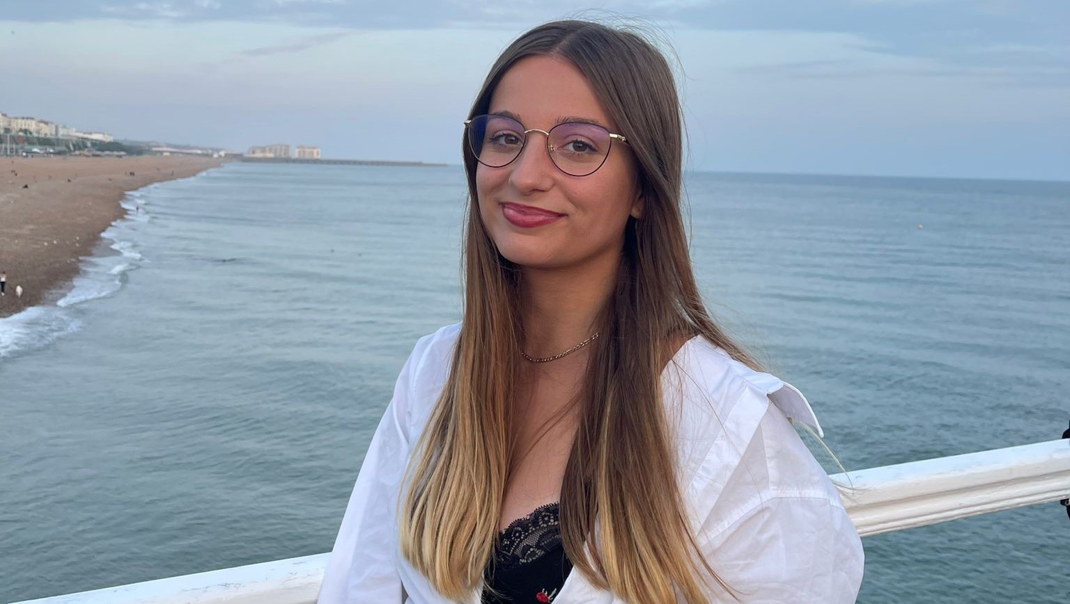 Girl standing in front of the sea smiling at the camera