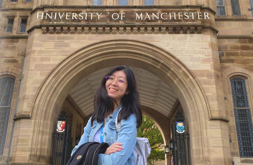 Girl smiling stand in front of the university of manchester building