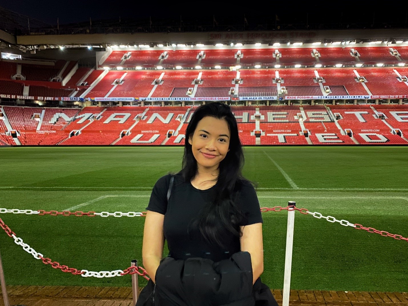 Female student smiling into camera in front of football pitch