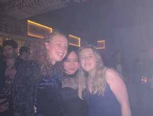 Three girls smiling at a camera whilst at a music event