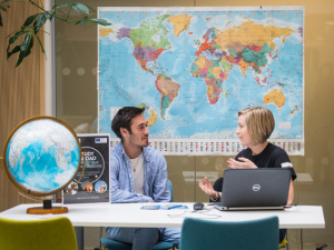 Male and female having conversation in front of world map