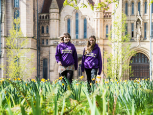 University of Manchester student ambassador walking through park, Whitworth Hall in background
