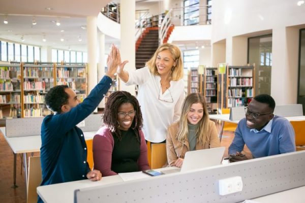 Picture of students smiling with a lecturer giving a high five.