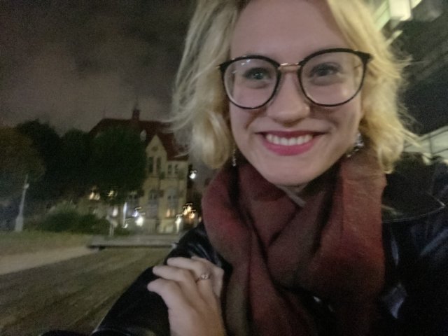Student with blonde hair and glasses smiling at the camera
