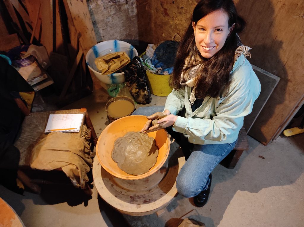 Student sat with a large bowl with clay surrounded by excavation materials