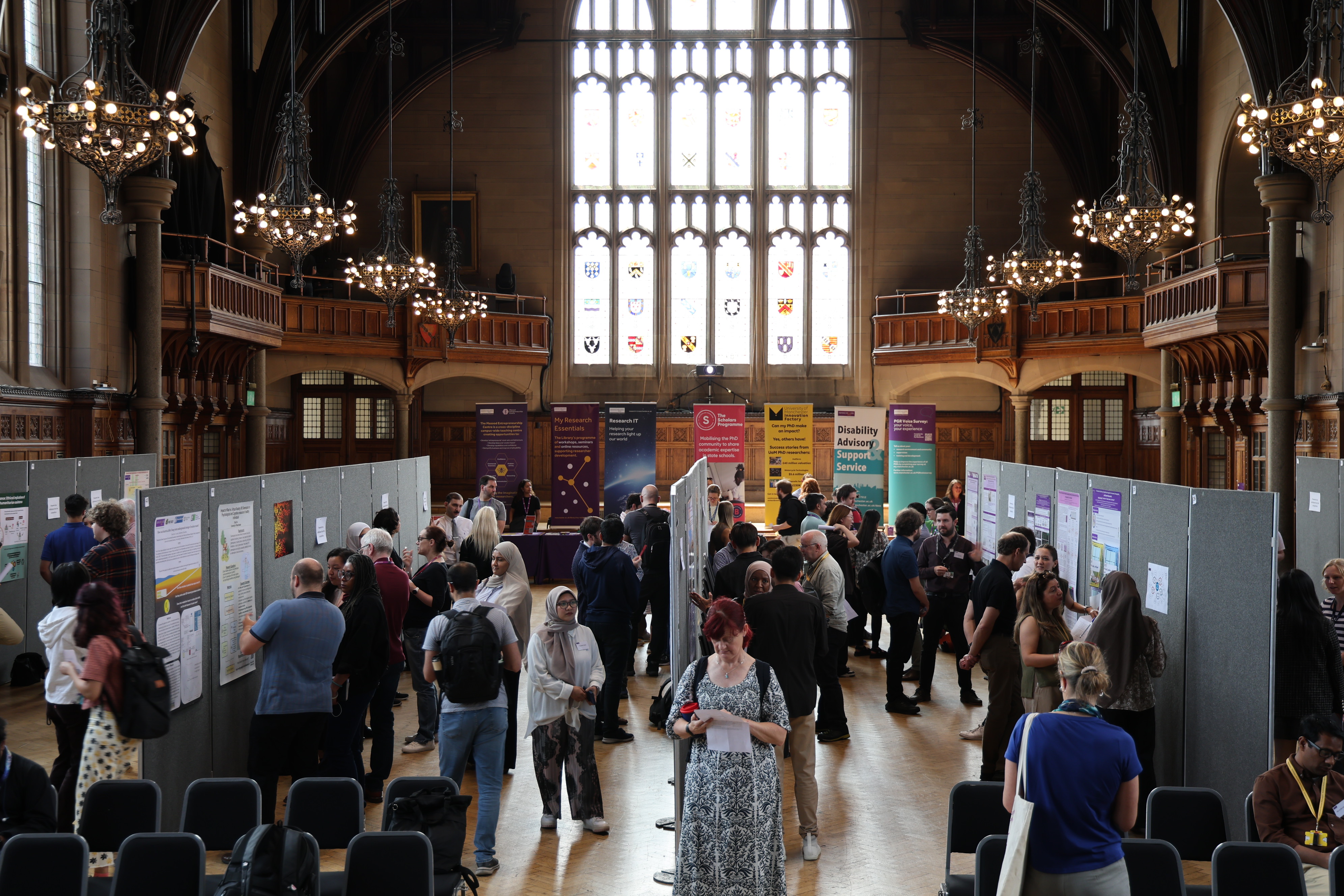 Wide shot of showcase A number of attendees klooking at research posters in a large display at Whitworth Hall