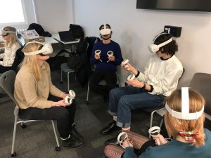 Seated students holding controllers and wearing VR headsets.