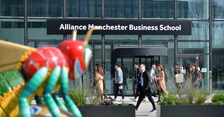 Exterior view of Alliance Manchester Business School entrance with Manchester bee in the foreground