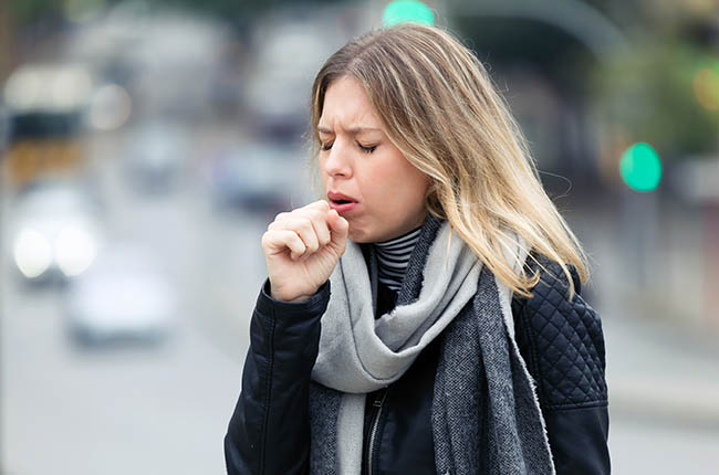A woman coughing in the street.