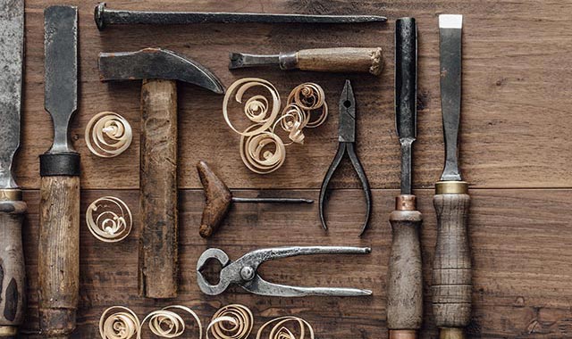 Collection of vintage woodworking tools lay flat on a rough workbench.