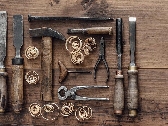 Collection of vintage woodworking tools lay flat on a rough workbench.
