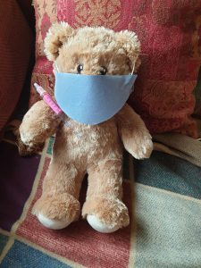teddy bear wearing a face mask holding a needle