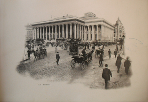 Black and white photograph of the exterior of a colonnaded public building, across a busy square with omnibuses and carriages.