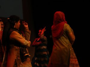 Ensemble performance of women on stage dancing to the Mehndi ceremony