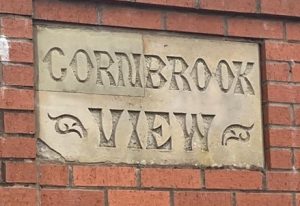 A stone sign with the words Cornbrook view carved. The sign is reclaimed from demolished terraced housing and it sits in the wall of Bennett Brothers scrap metal merchants at the western end of Cornbrook Road.