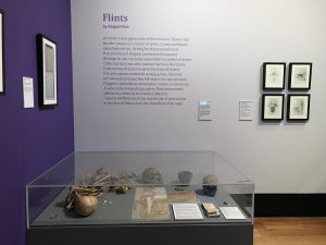 Image of poem titled 'Flints' by Abigail Flint, on wall beside archaeological display in Sheffield Weston Park Museum