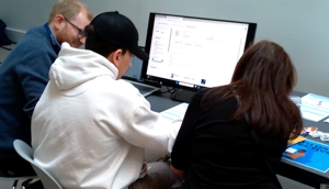 Three people at a computer.