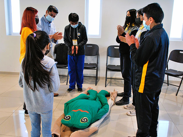 Boris Sáez, co-líder del proyecto enseña a estudiantes cómo usar una manta para mover a una “persona” herida en un desastre.